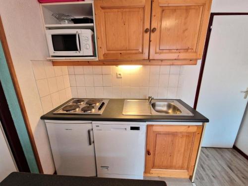 une petite cuisine avec un évier et un micro-ondes dans l'établissement Résidence Grand Argentier - 2 pièces +cabine 6/8 personnes coeur station 42m² MAE-2909, à Modane
