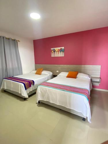 two beds in a room with a pink wall at Amoblados la 19 in Ríohacha