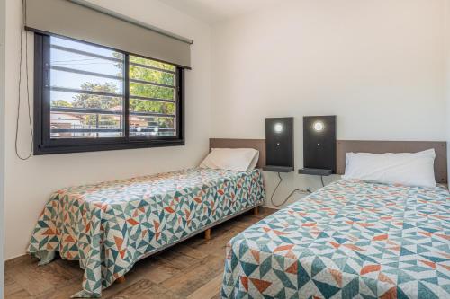 two beds in a room with a window at Tango Departamento in Santa Teresita
