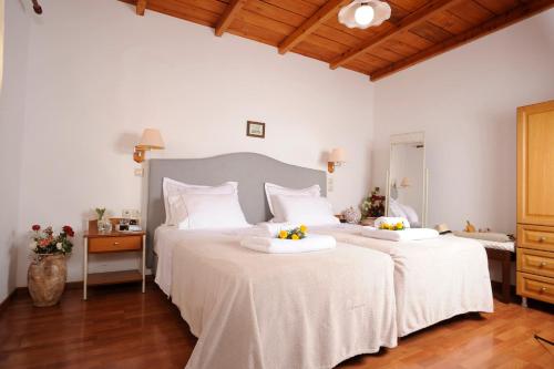 two beds in a bedroom with white walls and wood floors at Stefanos Village Hotel in Plakias