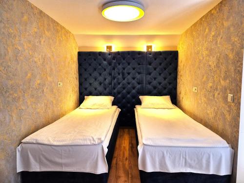 two twin beds in a room with a wall at Župė Dream House with jacuzzi and sauna in Klaipėda