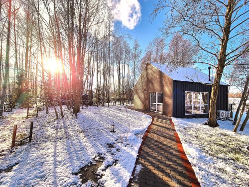 a house in the woods with snow on the ground at Župė Dream House with jacuzzi and sauna in Klaipėda
