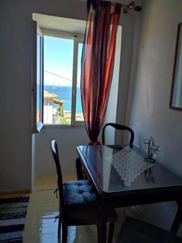 a glass table with a chair and a window at Traditional house near the sea in Platána
