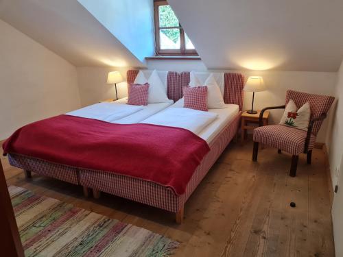 a bedroom with a large bed and two chairs at Sonnwirtstöckl am See in Sankt Gilgen
