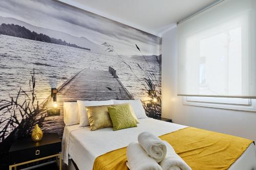 a bedroom with a bed with a painting of a pier at Apartamentos Plasencia Bambu in Plasencia