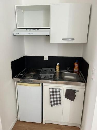 Il comprend une petite cuisine équipée d'une cuisinière et d'un évier. dans l'établissement Appartement cosy Armentières gare, à Armentières