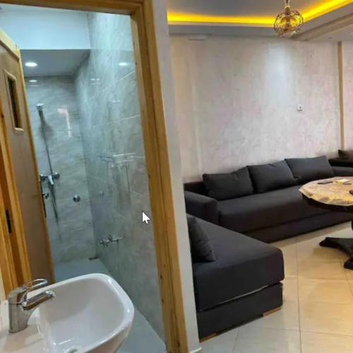 a bathroom with a shower and a sink and a couch at Appartements Chez Amdlou in Imsouane