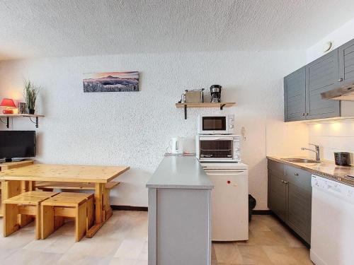 une cuisine avec une table en bois et une table et une cuisine avec un plan de travail dans l'établissement Les Chalets De La RosiÈre - Studio de 25m² pour 4 personnes MAE-4404, à Montvalezan