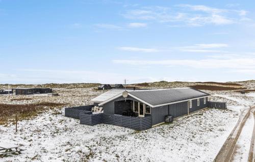 a small black house in the middle of a desert at Gorgeous Home In Thisted With Sauna in Klitmøller