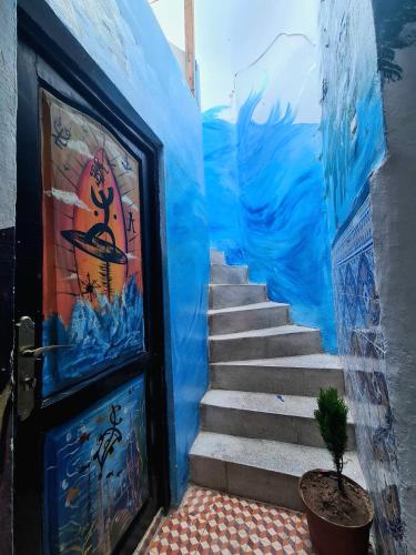 a stairway with a painting next to a door at Surfaces Hostel in Taghazout