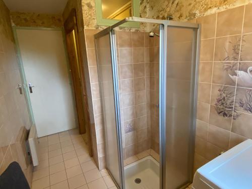 une douche avec une porte vitrée dans une salle de bain dans l'établissement Gite la Pomme de Pin bij boerderij, à Sazeray