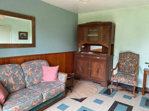 un salon avec un canapé et une chaise dans l'établissement Gite la Pomme de Pin bij boerderij, à Sazeray