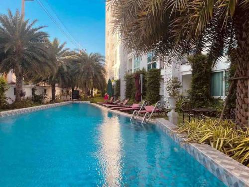 Una piscina con palmeras y un edificio. en Free Power&WiFi,Work Remotely, Kitchen,Deal, en Pattaya South