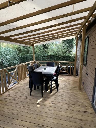 une terrasse en bois avec une table et des chaises dessus dans l'établissement Camping Del Mar B70, Mobile Home Excellence, 3 chambres, 6 personnes, 2 Salles de Bain, bord de mer, à Argelès-sur-Mer