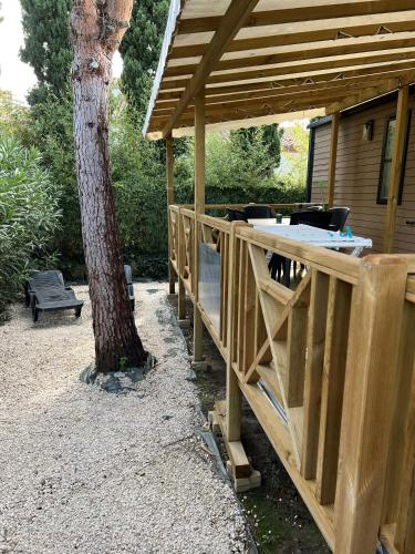un pavillon en bois à côté d'un arbre à côté d'une maison dans l'établissement Camping Del Mar B70, Mobile Home Excellence, 3 chambres, 6 personnes, 2 Salles de Bain, bord de mer, à Argelès-sur-Mer