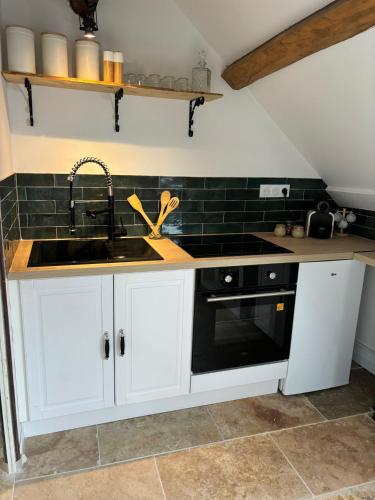 une cuisine avec des armoires blanches, un évier et une cuisinière dans l'établissement Hyper centre Sous les toits Auxerre, à Auxerre