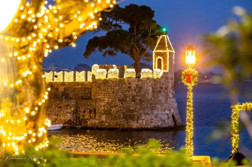 a street light with christmas lights in front of a castle at Helen's Seaside Apartment in Nafpaktos