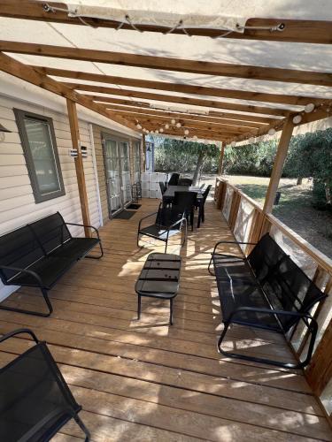 une terrasse en bois avec des chaises et des tables ainsi qu'une pergola dans l'établissement Camping Del Mar B10, Mobile Home Excellence, 3 chambres, 6 personnes, bord de mer, à Argelès-sur-Mer