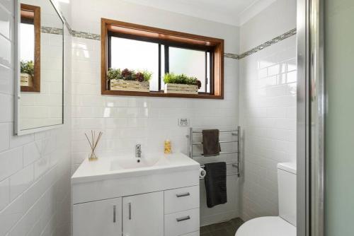a white bathroom with a sink and a toilet at Waterfront and direct beach access with views in Ulladulla