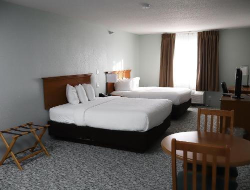 a hotel room with two beds and a table at Travelodge by Wyndham Rapid City - Black Hills in Rapid City