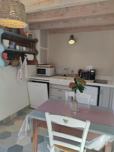 une cuisine avec une table avec un vase de fleurs dessus dans l'établissement Coccinelle, à Yronde-et-Buron