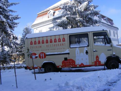 a food truck parked in front of a house in the snow at Bagolyvár Fogadó- Újfalusy Márton Vendégház in Zirc