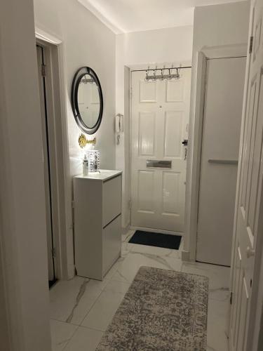 Un baño blanco con lavabo y espejo. en One Bedroom Flat in Chiswick W4, en Londres