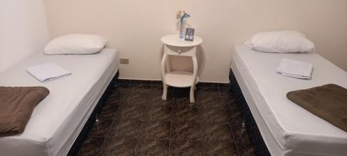 two beds in a room with a table and a chair at Hostel Blaese Pascal - HBP in Guarulhos