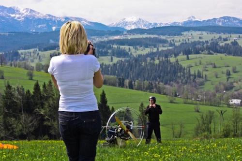 a woman taking a picture of a man on a hill at Miętowa Górka in Ząb