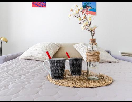 - un plateau avec 2 tasses et un vase avec des fleurs sur le lit dans l'établissement Résidence le Paga, à Nice