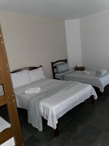 a bedroom with two beds with white sheets at Pousada Terra Do Sol in Arraial do Cabo
