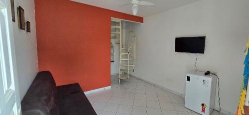 a living room with a red wall and a tv at Vila Mar Flats - 1 Dorm - Guriri - 800m da Praia in Guriri