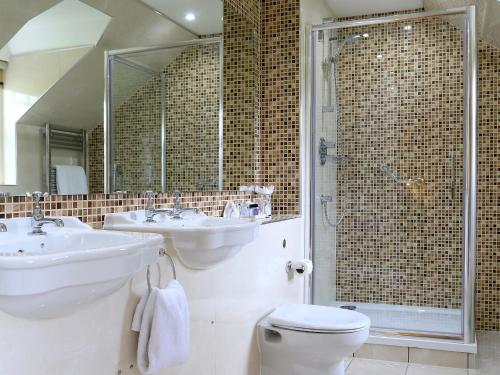 y baño con 2 lavabos, ducha y aseo. en Macdonald Pittodrie House en Chapel of Garioch