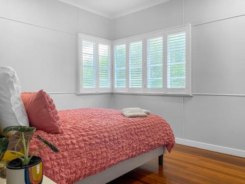 a bedroom with a bed with a pink blanket and two windows at Rose Cottage - Pet-Friendly Cottage in Jindalee