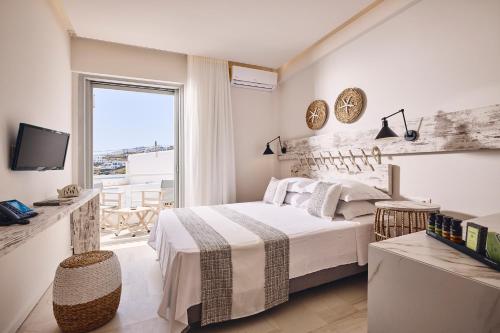 a white bedroom with a bed and a balcony at Kythnos Bay Hotel in Loutra