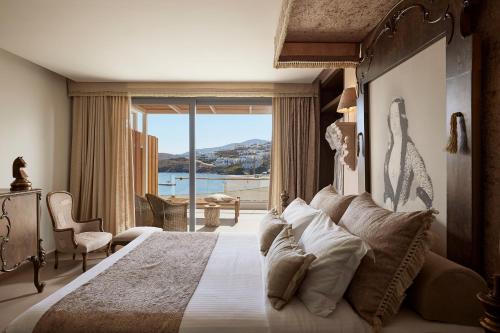 a bedroom with a large bed with a large window at Kythnos Bay Hotel in Loutra