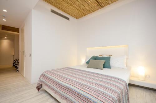 a white bedroom with a bed with a striped blanket at Thomais Studios in Naxos Chora