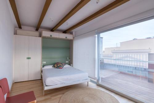 a bedroom with a bed and a large window at Àtic la Llotja in Tortosa