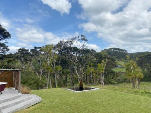 a grassy yard with stairs and trees in the background at Bethells Luxury Retreat - Auckland Glamping in Auckland