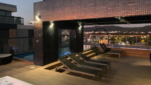 a rooftop deck with chairs and a swimming pool at Apto Elegante com Localização Privilegiada e Rooftop incrível in Florianópolis