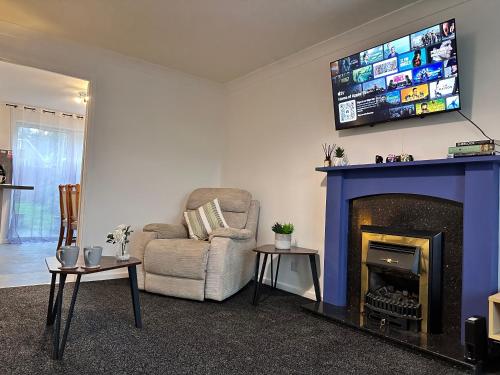 a living room with a couch and a tv above a fireplace at Detached 3-Bedroom Home in a Quiet Derby Neighbourhood in Mickleover in Derby