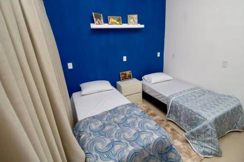a bedroom with two beds and a blue wall at Casa próxima aos pontos turísticos in Foz do Iguaçu