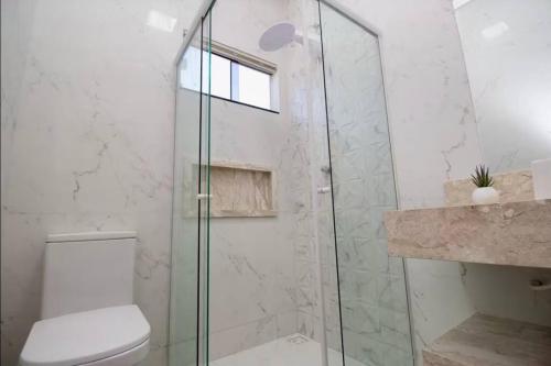 a bathroom with a toilet and a glass shower at Casa próxima aos pontos turísticos in Foz do Iguaçu