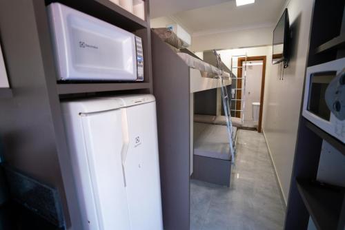 a small room with a bed and a microwave at Pousada Mirante do César in Bombinhas