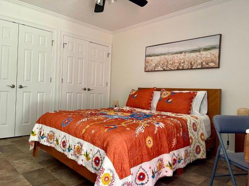ein Schlafzimmer mit einem Bett mit einer orangefarbenen Bettdecke in der Unterkunft Cozy Condo in Lake Charles