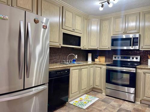 eine Küche mit Holzschränken und einem Edelstahlkühlschrank in der Unterkunft Cozy Condo in Lake Charles