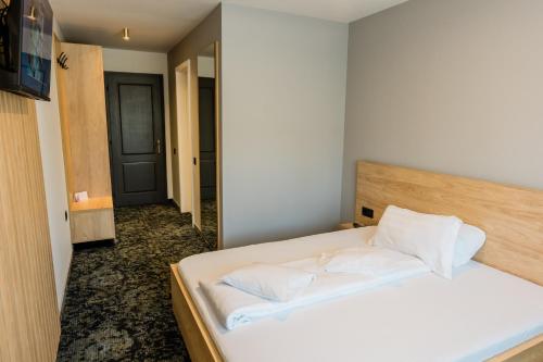 a bedroom with a white bed with a wooden headboard at Complex Turistic Capus & Spa in Căpuşu Mare