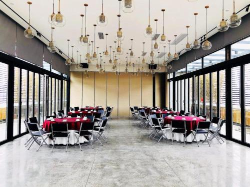 a conference room with red tables and chairs and windows at James Joyce Coffetel Chengdu Jichang Road Shenxianshu in Chengdu