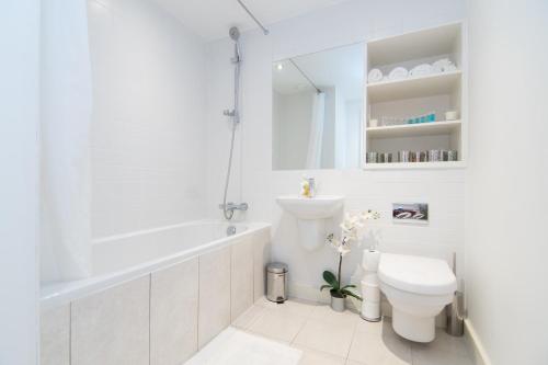 a white bathroom with a tub and a toilet at Mitchell Street Glasgow Apartment in Glasgow