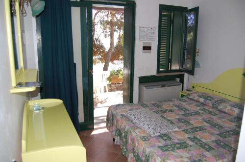 a bedroom with a bed and a door to a patio at Hotel Club Torre Capovento in Sperlonga